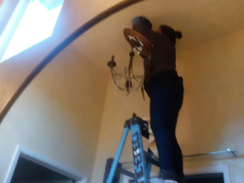 Electrician installing a chandelier in a Lockhart residence